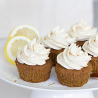 Cupcakes with lemon frosting on a white plate with lemon slices.