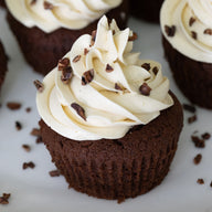 Chocolate cupcakes with vanilla buttercream and cacao nibs on a white plate