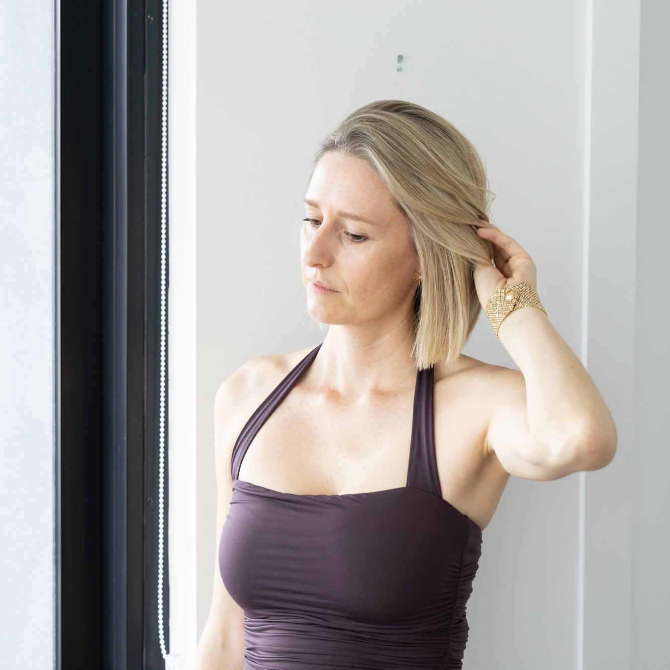 Woman adjusting her cool blonde foiled hair in front of a mirror